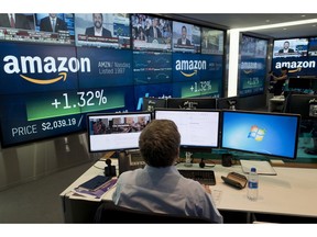 FILE- In this Sept. 4, 2018, file photo a Nasdaq employee monitors market activity in New York. Companies around the country and across industries are in the midst of reporting another quarter of gargantuan profit growth, driven by lower tax bills and a growing economy. Amazon said its net income surged more than tenfold during the summer from a year earlier, for example.