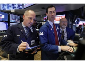 FILE- In this Friday, Nov. 9, 2018, file photo trader Michael Urkonis. left, works with specialists John McNierney, center, and Douglas Johnson on the floor of the New York Stock Exchange. The U.S. stock market opens at 9:30 a.m. EDT on Wednesday, Nov. 21.