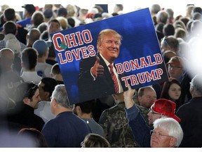 In this March 14, 2016 photo, a supporter of Republican presidential candidate Donald Trump holds a sign during a plane-side rally at Youngstown-Warren Regional Airport in Vienna, Ohio. It was working-class voters who bucked the area's history as a Democratic stronghold and backed Donald Trump in 2016, helping him win the White House with promises to put American workers first and bring back disappearing manufacturing and steel jobs. Whether they stick with him after this week's GM news and other signs that the economy could be cooling will determine Trump's political future.