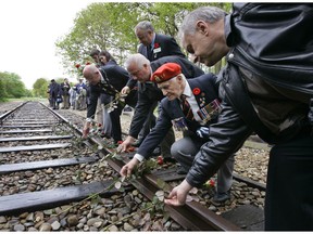 In this Monday May 9, 2015, file photo, Canadian World War II veterans put roses on the railroad tracks at former concentration camp Westerbork, the Netherlands, Monday May 9, 2005. The veterans observed a minute of silence remembering more than a hundred thousand Jews who were transported from Westerbork to Nazi death camps. The Dutch national railway company NS says it will set up a commission to investigate how it can pay individual reparations for its role in mass deportations of Jews by Nazi occupiers during World War II.