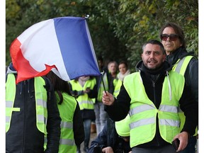 Demonstrators, called the yellow jackets, protest against the rising of the fuel taxes as French interior minister Christophe Castaner visits a police barrack in Cenon, near Bordeaux, southwestern France, Thursday, Nov. 29, 2018.