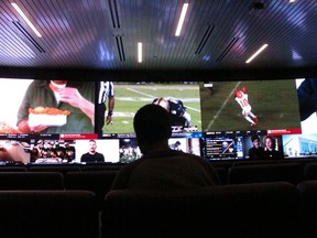 In this Nov. 20, 2018, photo a customer watches video screens at the sports betting facility at Resorts Casino in Atlantic City, N.J. Professional sports leagues that once vehemently fought sports betting are now partnering with gambling companies to get in on it now that it's legal.