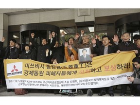 Korean victims of Japan's forced labor and their family members raise their hands in celebration after the Supreme Court's ruling ordering Japan's Mitsubishi Heavy Industries to compensate them in Seoul, South Korea, Thursday, Nov. 29, 2018. South Korea's top court has ordered a Japanese company to compensate 10 Koreans for forced labor during Tokyo's 1910-45 colonial rule of the Korean Peninsula. The signs read: " Mitsubishi Heavy Industries apologizes and compensates to victims."