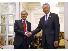 Malaysia's Prime Minister Mahathir Mohamad, left, shakes hands with Singapore's Prime Minister Lee Hsien Loong at the Istana in Singapore, Monday, Nov. 12, 2018.