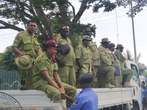 Security personnel on the back of a truck wait to be paid at Rita Flynn Netball Centre in Port Moresby, Papua New Guinea, Tuesday, Nov. 20, 2018.. Opposition lawmaker Bryan Kramer said disgruntled police and prison guards stormed Papua New Guinea's Parliament in a pay dispute that stemmed from an international summit hosted by the South Pacific island nation last weekend.