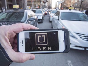 The Uber logo is seen in front of protesting taxi drivers who were depositing a request for an injunction against the ride sharing company at the courthouse Tuesday, February 2, 2016 in Montreal.