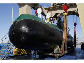 In this photo provided by the semiofficial Mehr News Agency, Iran's navy members stand on Ghadir-955 submarine during its inauguration in the southern port of Bandar Abbas, Iran, at the mouth of the strategic Strait of Hormuz, Thursday, Nov. 29, 2018. Iran's navy has acquired two new mini submarines designed for operations in shallow waters such as the Persian Gulf, the Iranian state TV reported on Thursday.