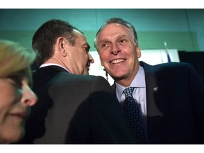 Virginia Gov. Ralph Northam, center, talks with former Virginia Gov. Terry McAuliffe, right, before the start of a news conference in the Crystal City neighborhood in Arlington, Va., Tuesday, Nov. 13, 2018. Amazon, which has grown too big for its Seattle hometown, said it will split its much-anticipated second headquarters between New York and northern Virginia.