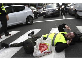 A demonstrator, called the yellow jackets, lays in a pedestrian crosswalk as he protests against rising fuel prices in Brussels, Friday, Nov. 30, 2018