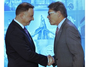 Poland's President Andrzej Duda, left, and U.S. Energy Secretary Rick Perry, right, shake hands during a ceremony in which Poland's main gas company PGNiG signed a long-term deal for liquefied gas deliveries with the U.S. firm Chenier, in Warsaw, Poland, Thursday, Nov. 8, 2018.