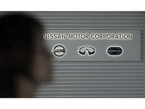 A woman walks past the logos of Nissan Motor Co. at Nissan Motor Co. Global Headquarters in Yokohama near Tokyo Wednesday, Nov. 21, 2018.  France's Renault says it has decided to keep its CEO Carlos Ghosn on despite his arrest in Japan on allegations that he misused assets of partner Nissan Motor Co. and misreported his income. Renault's board of directors announced late Tuesday that the No. 2 at the company, Chief Operating Officer Thierry Bollore, would temporarily fill in for Ghosn.