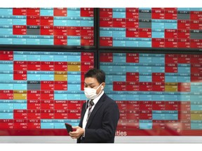 A man walks past an electronic stock board showing Japan's Nikkei 225 index at a securities firm in Tokyo Friday, Nov. 16, 2018. Shares were mixed in early trading in Asia on Friday on revived concerns over the prospects for a breakthrough in trade tensions between the U.S. and China.
