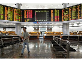 An Investor walks in front of private stock trading boards at a private stock market gallery in Kuala Lumpur, Malaysia, Friday, Nov. 23, 2018. Asian markets are mostly lower as traders dwelled on risks from a drawn-out dispute between the U.S. and China and other events closer to home.