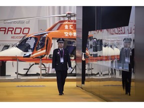 A security guard walks past a helicopter displayed at the China International Import Expo held in Shanghai, Monday, Nov. 5, 2018. Chinese President Xi Jinping has promised to open China's market wider as he opened a trade fair meant to promote the country's image as an importer, but he offered no response to U.S. and European complaints about technology policy and curbs on foreign business.
