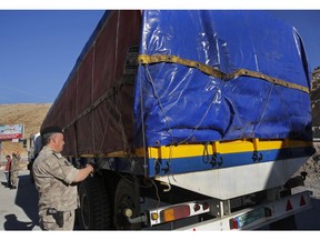 In this Oct. 31, 2018 photo, a Lebanese customs officer stamps a truck waiting to cross into Syria from the Lebanese border crossing point of al-Masnaa, in Bekaa Valley, Lebanon. The long-awaited reopening of a vital border crossing between Syria and Jordan earlier this month was supposed to bring relief to Lebanese farmers and traders looking to resume exports to Gulf countries. But the commerce has so far been complicated by politics, high transit fees and fighting over which trucks pass through which country.