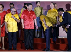 Papua New Guinea's Prime Minister Peter O'Neill, left, and Chinese President Xi Jinping watch as Malaysian Prime Minister Mahathir Mohamad looks for his spot at a family photo with leaders and their spouses during the APEC Economic Leaders Meeting summit in Port Moresby, Papua New Guinea, Saturday, Nov. 17, 2018.