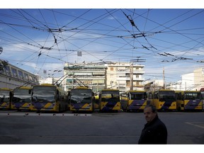 A man walks past by parked electric trolley buses in a depot during a 24-hour strike organized by GSEE, the biggest labor union representing the entire private sector and many public sector workers in Athens on Wednesday, Nov. 28, 2018. Unions want the left-led government to ditch key elements of the austerity packages that were imposed in waves since 2010 to balance the country's public finances, under pressure from international bailout creditors.