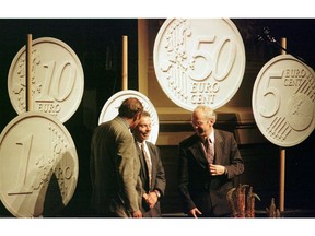 FILE - In this Monday, June 16, 1997 file photo, Belgian designer Luc Luycx, centre, is surrounded by the new Euro coins he designed during a presentation in Amsterdam. At left is European financial affairs commissioner Yves-Thibauld De Silguy, and Dutch Finance Minister Gerrit Zalm, right. Europe's experiment with sharing a currency is turning 20 in a few days. The euro is credited with increasing trade between members. But countries have struggled to adjust to trouble after giving up two big safety valves: the ability to let their currency's exchange rate fall to boost exports, and to adjust own interest rates to stimulate business activity.