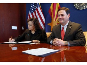 New Mexico Gov. Susana Martinez, left, signs an agreement to a cross-border plan to provide natural gas to Asia as Arizona Gov. Doug Ducey, R, looks on, Wednesday, Dec. 19, 2018, at the Capitol in Phoenix.