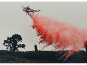 FILE - In this Aug. 13, 2016 file photo, a fire attack helicopter makes a retardant drop during a firing operation on the ridge between Mount Manuel and the Coast Ridge Road while fighting the Soberanes Fire near the village of Big Sur, Calif. The so-called Soberanes Fire burned its way into the record books as the most expensive wildland firefight in U.S. history in what a new report calls "an extreme example of excessive, unaccountable, budget-busting suppression spending that is causing a fiscal crisis in the U.S. Forest Service."