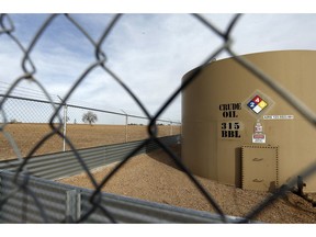 In this Feb. 13, 2017 file photo, a crude oil storage tank sits behind a fence at a petroleum extraction site near Mead, Colorado. A new report from the National Energy Board says the "primary factor" in recent steep discounts on western Canadian crude is that oil production outstrips export pipeline capacity by about 365,000 barrels per day.