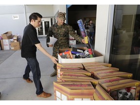 Sgt. Christian Pastrana, right, prepares toys for a donation to the organization Women in Distress, at the Marine Corps Toys for Tots depot, Wednesday, Dec. 19, 2018, in Hialeah, Fla. The recent closure of Toys R Us created some collateral damage -- the Toys for Tots charity drive. More than 250,000 toys donated by consumers and $5 million, 40 percent of corporate giving, came through Toy R Us last year, holes the annual Marine Corps' community effort is working to fill. At left is Matthew Williams, picking up the donation for Women in Distress.