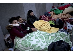 Wesam, left, and Ismail, second left, no surnames given, both from Gaza Strip, shelter with blankets against the cold as they queue with others outside an asylum seeker reception centre during the international migrants day, in Brussels, Tuesday, Dec. 18, 2018. Wesam and Ismail, who have been queueing for four days, claimed that it's taken them six months journey from Gaza Strip to Belgium crossing several countries such a Egypt, Turkey, Greece, Albania, Bosnia-Herzegovina, Croatia, Slovenia, Italy, France and finally Belgium.