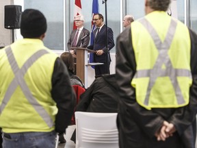 Oil field workers watch as Canada's Minister of International Trade Diversification Jim Carr, left, Canada's Minister of Natural Resources Amarjeet Sohi, centre and Randy Boissonnault, Edmonton M.P. speak during press conference to announce support for Canada's oil and gas sector, in Edmonton on Tuesday, Dec. 18, 2018.