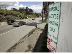 FILE - In this April 20, 2007 file photo a sign directing visitors to two parking spaces next at a coastal access gate for Escondido Beach is shown on Pacific Coast Highway in Malibu, Calif. A new smartphone app that shows users a map of more than 1,500 access points along the California coast was created with help from a tech billionaire whose elaborate wedding ran afoul of state regulators.