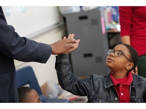 In this Tuesday, Dec. 18, 2018 photo, second grader Maleki Ratliff high-fives Jamar McKneely, chief executive officer of InspireNOLA Charter Schools, at Alice M. Harte Charter School in New Orleans. Charter schools, which are publicly funded and privately operated, are often located in urban areas with large back populations, intended as alternatives to struggling city schools.