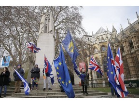 Anti-Brexit demonstrators wave flags outside the houses of Parliament in London, Wednesday Dec. 19, 2018.