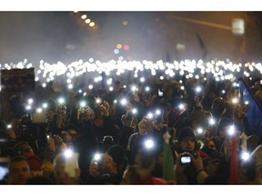 Anti-government demonstrators light up their mobile phones during their protest in the downtown of Budapest, Hungary, Sunday, Dec. 16, 2018.