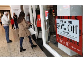 FILE - In this Dec. 24, 2018, file photo, discount placards stand in the window of a clothing store as last-minute shoppers finish up their Christmas gift lists at the Cherry Creek Mall in Denver. Americans buoyed by a strong economy pushed holiday sales growth to a six-year high.