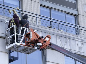 FILE- In this Oct. 18, 2018 file photo, workers remove the Trump Place sign from building on New York City's Upper West Side. Adding to the evidence that the Trump presidency has hurt the Trump brand, several buildings have stripped the Trump name off their entrance since the president took office.