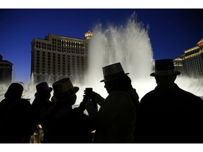 FILE - In this Dec. 31, 2015, file photo, people watch the fountains at the Bellagio while wearing paper hats to celebrate New Years Eve in Las Vegas. Las Vegas will usher in 2019 trying to outdo itself with performances by Lady Gaga, Gwen Stefani, Bruno Mars and other superstars at the city's various venues. More than 300,000 people are expected to gather Monday, Dec. 31, 2018, on the world-famous Las Vegas Strip to watch 8 minutes of fireworks.