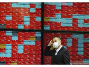 In this Nov. 7, 2018, photo, a man walks past an electronic stock board showing Japan's Nikkei 225 index at a securities firm in Tokyo. Asian markets tumbled on Friday, Dec. 14, 2018 after China reported weaker-than-expected economic data, stirring up worries about the state of the world's second largest economy.