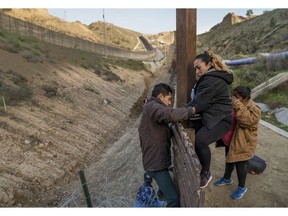 A pregnant migrant climbs the border fence before jumping into the U.S. to San Diego, Calif., from Tijuana, Mexico, Thursday, Dec. 27, 2018. Discouraged by the long wait to apply for asylum through official ports of entry, many Central American migrants from recent caravans are choosing to cross the U.S. border wall and hand themselves into border patrol agents.