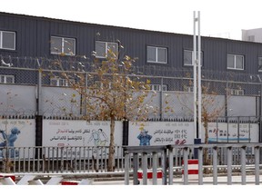 In this Wednesday, Dec. 5, 2018, photo, two layers of barbed wire fencing ring the "Hotan City apparel employment training base" where Hetian Taida has a factory in Hotan in western China's Xinjiang region. This is one of a growing number of internment camps in the Xinjiang region, where by some estimates 1 million Muslims are detained, forced to give up their language and their religion and subject to political indoctrination. Now, the Chinese government is also forcing some detainees to work in manufacturing and food industries. Some of them are within the internment camps; others are privately owned, state-subsidized factories where detainees are sent once they are released.