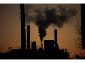 Smoke billows from a chimney of the Solvay factory for production and processing of plastic materials, in Ospiate, near Milan, Italy, Friday, Dec. 14, 2018. The climate change conference, COP24, is closing today in Katowice, Poland.