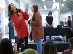 Social media influencer Sabrina Tan, left, jokes with a shopper during a demonstration for shoppers on how to apply lipstick.