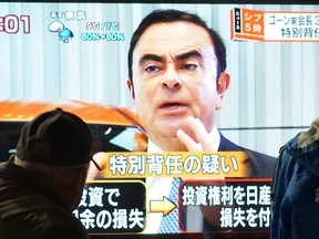 Passersby look at a television screen showing a news program featuring former Nissan chief Carlos Ghosn in Tokyo on Friday. Ghosn was re-arrested over fresh allegations, apparently dashing his hopes of early release.