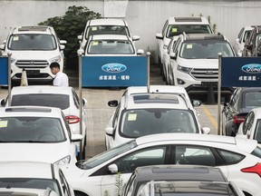 A man walks past Ford Motor Co. vehicles on display at a car dealership in Shanghai. A proposal to reduce tariffs on cars made in the U.S. to 15 per cent from the current 40 per cent has been submitted to China's Cabinet to be reviewed, sources say.