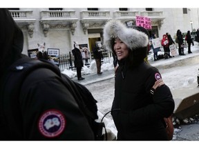 A woman wearing a Canada Goose jacket walks past PETA protesters in front of the New York Stock Exchange during the Canadian company's IPO, Thursday, March 16, 2017. The People for the Ethical Treatment of Animals is threatening to sue the City of Toronto and Astral Media for removing anti-Canada Goose ads.