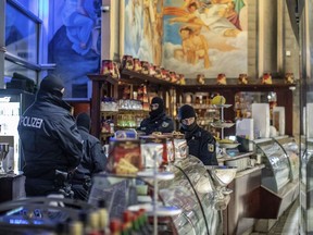 Masked police stand in an ice parlor in Duisburg, western Germany, Wednesday, Dec. 5, 2018 as authorities conduct coordinated raids in Germany, Italy, Belgium and the Netherlands in a crackdown on the Italian mafia.