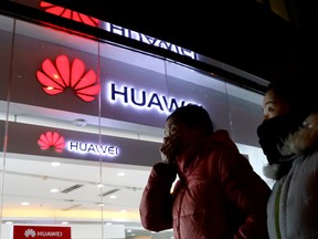 Women walk past a Huawei retail shop in Beijing Thursday, Dec. 6, 2018. China on Thursday demanded Canada release a Huawei Technologies executive who was arrested in a case that adds to technology tensions with Washington and threatens to complicate trade talks.
