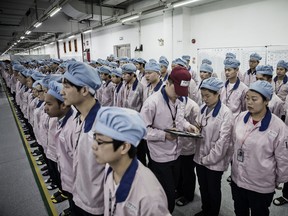 A supervisor checks an employee's badge during roll call at a Pegatron Corp. factory in Shanghai, China, where iPhones are made.
