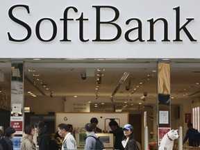 In this Tuesday, Dec. 4, 2018, photo, people walk past in front of a SoftBank shop at Ginza shopping district in Tokyo. Some users of SoftBank cellphones had problems calling and text messaging for several hours in Japan. SoftBank Corp. spokesman Naomasa Suzuki said the problems started early Thursday afternoon, Dec. 6, 2018, and were gradually being fixed. He said they were caused by a mechanical problem in the 4G telecommunications systems.