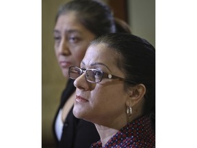 Victorina Morales, left, and Sandra Diaz, right, listen during an interview where they recalled their experience working at President Donald Trump's golf resort in Bedminster, N.J., Friday Dec. 7, 2018, in New York. The women say they used false legal documents to get hired and supervisors knew it.