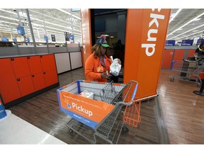FILE- In this Nov. 9, 2018, file photo Walmart associate Monique Mays places online orders in a pickup tower where customers can retrieve their purchases at a Walmart Supercenter in Houston. Plenty of major retailers are offering easier ways for customers to pick up items ordered online beyond the service desk. Walmart is adding lockers and big giant kiosks that spit out online orders.