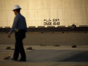 An employee walks past storage tanks for crude oil in the Juaymah tank farm at the Ras Tanura oil refinery and terminal, operated by Saudi Aramco, in Ras Tanura, Saudi Arabia.